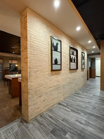 Textured light-coloured feature wall with framed art in a commercial interior